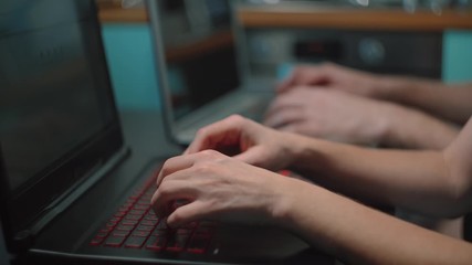 Close-up hands of freelance programmers on a laptop. Busy creative web designers are typing program code while working on in the office at home.