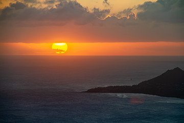 A sunset over the Hawaiian Island of Oahu as seen from a mountain top with Head in the distance.