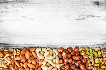 Nuts Mixed in a wooden white board.Variety of Walnuts, Almonds, Hazelnuts, Cashews, Pistachios. Concept of Healthy raw food selective focus.