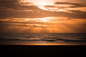 Dramatic Sunset Scene with Rays of Sun Light and Clouds over the Sea