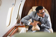 © LIGHTFIELD STUDIOS - nervous african american businessman holding paper bag while having panic attack during flight on private plane