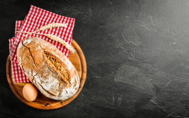 Wall Mural - Fresh bakery bread food, rustic crusty loaves of breads and buns on black stone background. Top view and copy space for text.