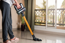 Woman Vacuuming The Living Room With Cordless Vacuum Cleaner