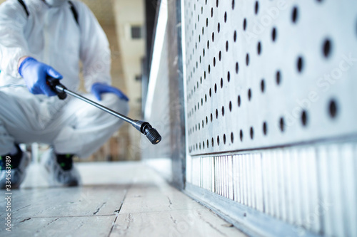 Fotografía Shot of an unrecognizable person in white chemical protection suit doing disinfection of public areas to stop spreading highly contagious corona virus