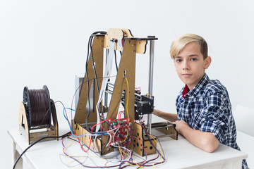 Education, children, technology concept - teen boy is printing on 3d printer.