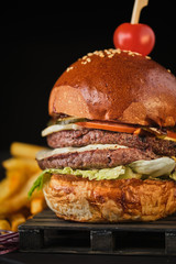 Wall Mural - Double beef cheeseburger with american french fries on a dark background.