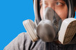 A man in a respirator mask with an increased degree of protection against harmful environmental factors. Full face mask. Isolate on a blue background.