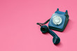 © George - Blue vintage antique rotary phone on a pink background with lifted handset receiver with copy space and room for text with a right side composition.