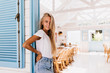 © Look! - Attractive tanned lady with gorgeous smile posing in cafeteria early in morning. Photo of cute young woman in vintage outfit standing in restaurant