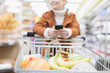 © Sam Edwards/Caia Image - Woman with smart phone pushing shopping cart in supermarket