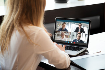 Wall Mural - back view of businesswoman speak using webcam conference on laptop with diverse colleagues, female e