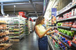 © Trevor Adeline/Caia Image - Woman with smart phone shopping in supermarket produce section