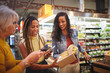 © Trevor Adeline/Caia Image - Women with smart phones shopping in supermarket