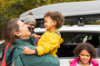 © Sam Edwards/Caia Image - Happy family hugging outside car in parking lot