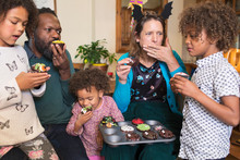 Multiethnic Family Eating Decorated Halloween Cupcakes