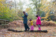 © Sam Edwards/Caia Image - Mother and daughters balancing on fallen log in autumn woods