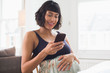 © Sam Edwards/Caia Image - Happy pregnant woman using smart phone