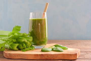 Wall Mural - A glass with a green smoothie and a bamboo cocktail straw is standing on a wooden board. Nearby are bunches of celery and spinach and parsley leaves. Useful snack. Vegan, vegetarian drink. Copy space