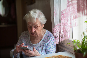 Wall Mural - An old woman with a smartphone in her hands.