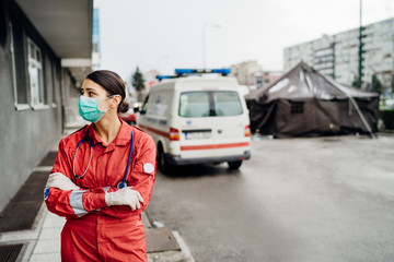 Sad overworked paramedic in uniform  in front of isolation hospital facility.Emergency room doctor in fear and psychological stress,pressure of fight against corona virus.Covid-19 mental health toll