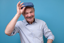 Cheerful Senior Man Greets By Taking Off A Hat