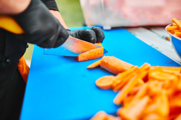 man in black gloves slices carrots