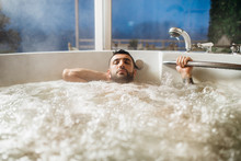 Man Relaxing At Home In The Hot Tub Bath Ritual.Spa Day Moment In Modern Bathroom Indoors Jacuzzi Tub.Body Care.Good Personal Hygiene Routine.Skincare,spa,aromatherapy.Bath Essential Oils.Antistress