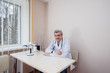 © Andrii - An experienced elderly doctor sits at a table in his bright office. A virus, and an epidemic
