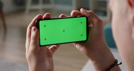 Wall Mural - Man using a smart phone with mock up green screen, talking while having an online conference - online education, communications concept close up 4k video template
