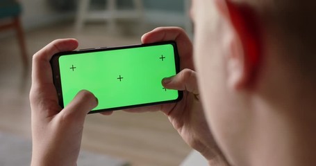 Wall Mural - Close up shot of man playing video games on his smart phone with chroma key green screen, quickly tapping on display - connection, technology concept 4k video template