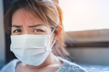 Sick asian woman have hight fever flu wear mask,have concern infection, look at camera on bed in bedroom, ,Global healthcare and prevent the spread infection corona virus concept, Selective focus.