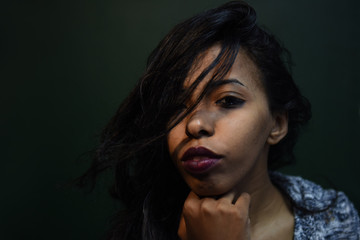 Wall Mural - young african woman posing at studio, face with hand portrait over dark background	