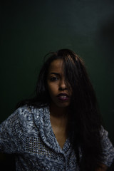 Wall Mural - young african woman posing at studio, face with hand portrait over dark background	