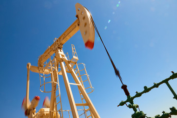 Wall Mural - Oil pump are working in the blue sky background. Blur effect. World Oil Industry. Western region of Kazakhstan.