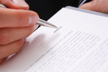 Male arm in suit offer contract form on clipboard pad and silver pen to sign closeup. Strike a bargain for profit, white collar motivation union decision corporate sale insurance agent concept