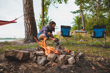 Wall Mural - couple resting near bonfire. woman cooking outdoors on fire