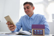 © H_Ko - A businessman realtor keeps smartphone in hand communicates with clients looking for tenants sells vacant new apartments with modern homes uses a mobile application to search for orders in a chat room