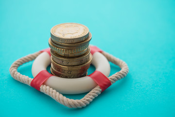 Wall Mural - Stacked coins in red lifebuoy or lifebelt with blue background copy space. Assets wealth, money saving or money investment protection and security by insurance concept. Risk management analysis.