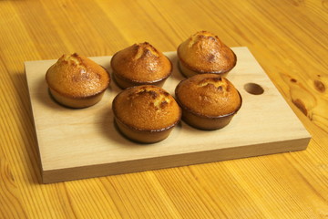 Five golden pies on a wooden board on a wooden table from boards.