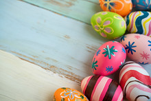 Flat Lay Of Colorful Vibrant Red Green Pink And Orange Easter Eggs With Stripe And Flower Pattern Painted On, Laying On Side Of Blue Wooden Table Background Representing Celebration Easter Holidays
