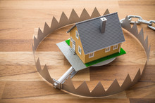 Mortgage House In A Trap On Wooden Table Background. House Trap On Debt Or Loan Problem Or Risk In Real Estate Property Financing Concept.