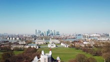 Aerial drone bird eye flight over the Royal Greenwich Observatory through the isle of dogs canary wharf district in London in a sunny day with blue sky