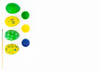 The concept of celebrating Easter. Workplace with cans of paint and colored painted eggs on white background. Copy space. Isolated. Top view