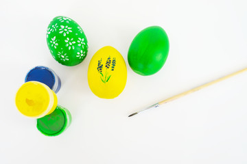 Wall Mural - The concept of celebrating Easter. Workplace with cans of paint and colored painted eggs on white background. Copy space. Isolated