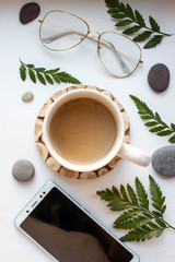 Wall Mural - phone mockup with coffee and leaves on white table