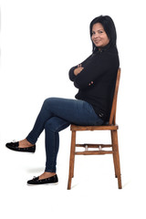 Wall Mural - portrait of a woman sitting on a chair in white background, legs and arms crossed ,looking at camera