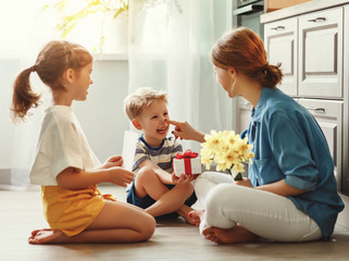 Wall Mural - happy children giving card and flowers to mother