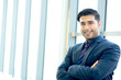 © methaphum - Portrait Handsome confident businessman wearing suit standing Successful businessman with folded arms  standing over office background. caucasian looking at camera. joyful smile with copy space.