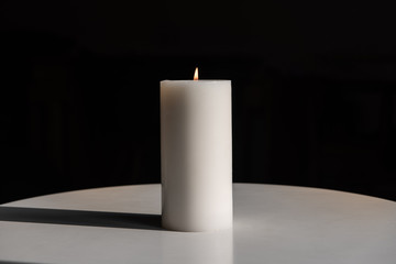 big white candle on a white table on a wooden background