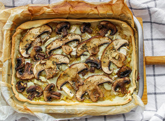 Poster - Mushroom tart baked in a metal tray and served on a wooden board. Healthy and crunchy veggie tart on marble table. 